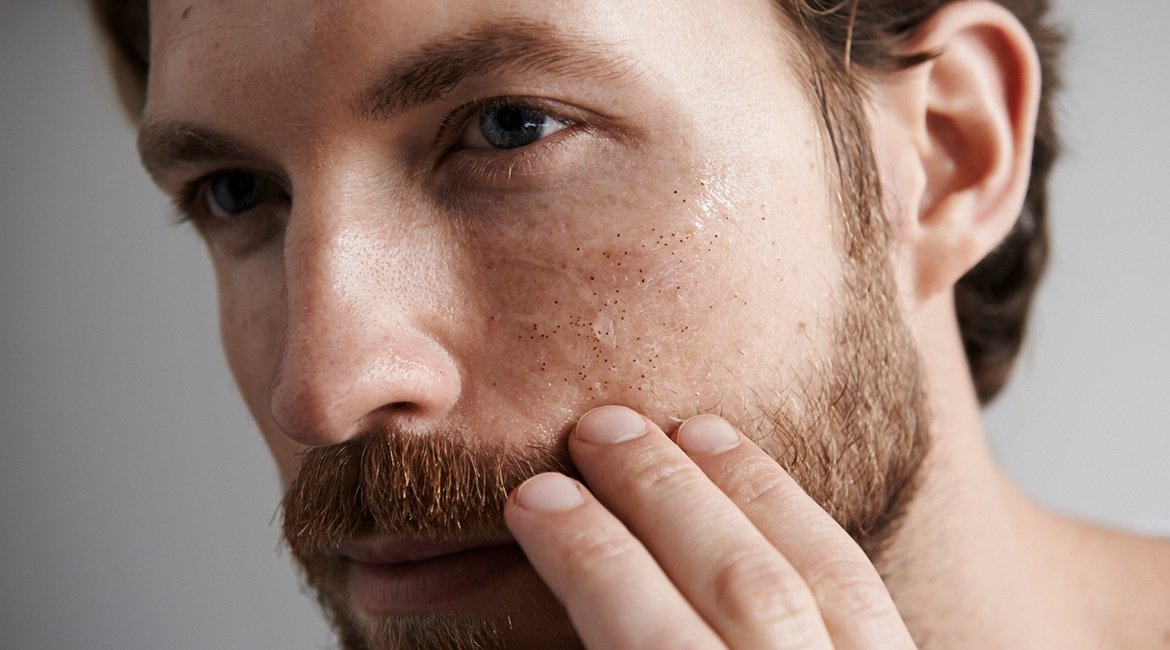 Ein Mann betrachtet sein Gesicht im Spiegel